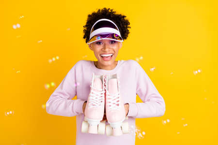 Photo of funny cheerful dark skin lady hands demonstrate rollers have good mood isolated on yellow...