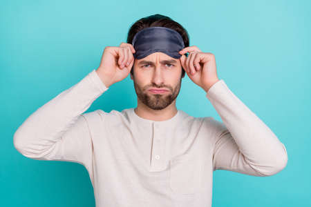 Photo of young man unhappy negative moody sleepy wear eye mask isolated over turquoise color backgroundの写真素材