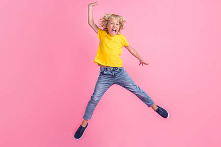 Full length photo of young excited small boy happy positive smile jump up yell isolated over pink...