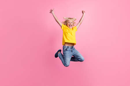 Full body photo of young cheerful school boy happy positive smile jump rejoice victory isolated over pink color backgroundの写真素材