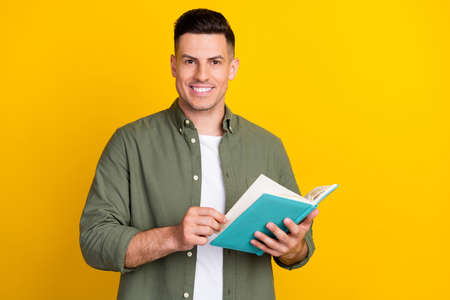 Photo portrait man smiling keeping book reading novel isolated vibrant yellow color background