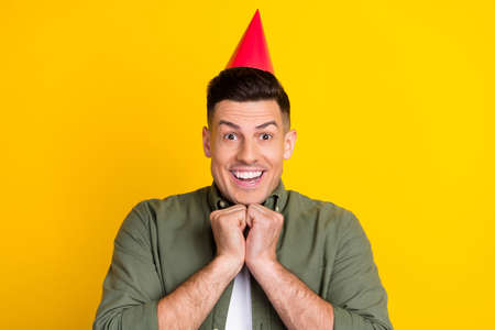 Photo of young guy happy positive smile celebrate birthday party cone isolated over yellow color backgroundの写真素材