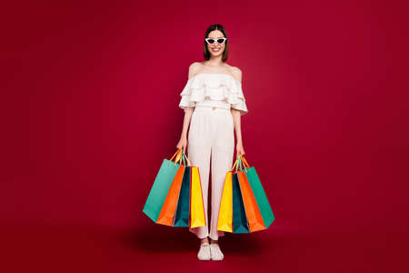 Full length photo of nice brown hairdo young lady with bags wear eyewear top pants isolated on red backgroundの写真素材