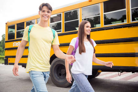 Photo of two funny sweet brother sister wear casual clothes backpack ready school smiling outdoors...