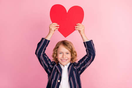 Photo of young little boy happy positive smile hold heart figure cupid valentine day isolated over pastel color backgroundの写真素材