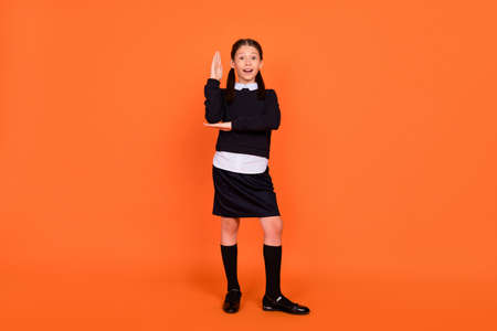 Full body photo of young school girl happy positive smile rise hand answer lesson isolated over orange color backgroundの写真素材