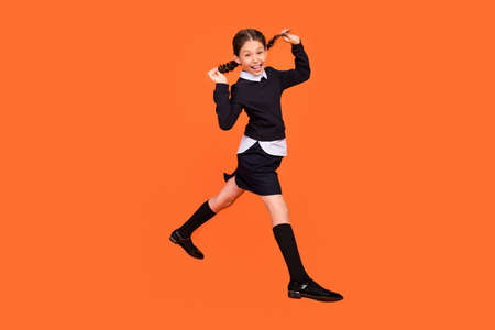 Full size profile side photo of young girl happy positive smile have fun playful jump isolated over orange color backgroundの写真素材