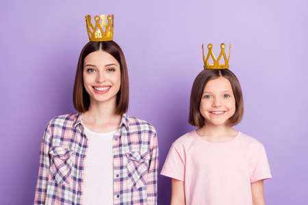Portrait of two attractive cheerful girls wearing crown best friends isolated over purple violet...