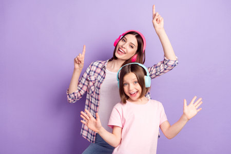 Portrait of two attractive cheerful girls listening melody rest dancing having fun isolated over purple violet color backgroundの写真素材