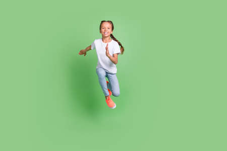 Full length body size photo little girl jumping high running fast smiling isolated pastel green color backgroundの写真素材