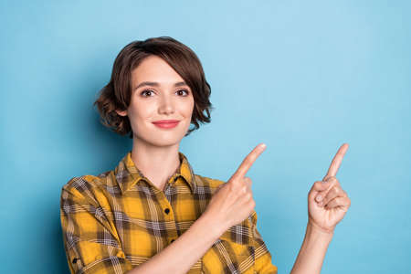 Photo of adviser girl indicate forefinger empty space promote sale wear plaid shirt isolated blue color backgroundの写真素材