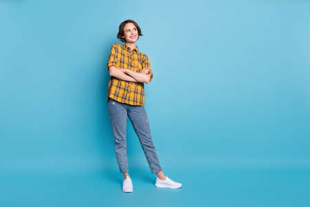 Photo of dreamy creative lady folded arms look empty space wear plaid shirt jeans shoes isolated blue color backgroundの写真素材