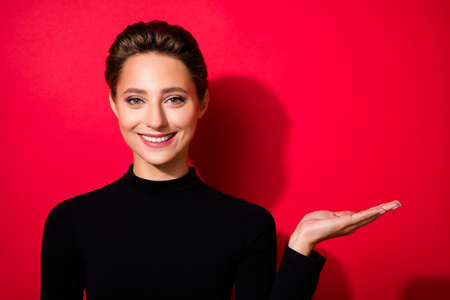 Portrait of attractive cheerful brown-haired girl holding on palm copy empty space isolated over...