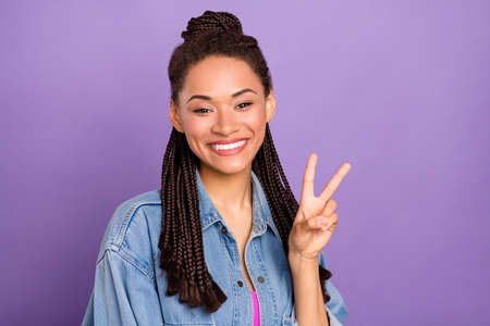 Portrait of attractive cheerful brunette toothy girl showing v-sign isolated over bright purple violet red color backgroundの写真素材