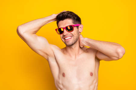 Photo of cool brunet millennial guy touch head wear eyewear isolated on yellow color backgroundの写真素材