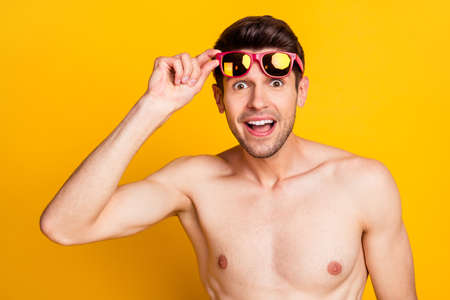 Photo of charming impressed young guy shirtless arm dark glasses smiling isolated yellow color backgroundの写真素材