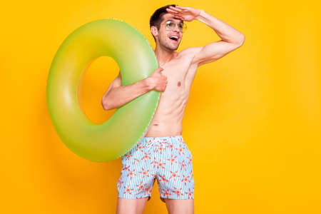 Photo of curious cute man naked torso dark eyewear arm forehead looking far away empty space smiling isolated yellow color backgroundの写真素材
