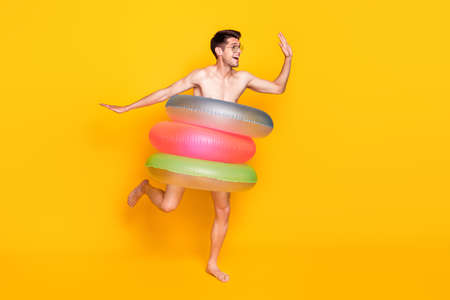 Photo of positive funny man naked torso wear dark eyewear standing inside water circle waving arm isolated yellow color backgroundの写真素材