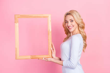 Photo of happy nice positive young woman hold hands frame copyspace smile isolated on pink color...