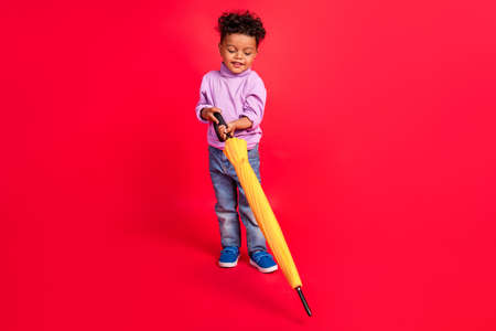 Full length body size view of attractive cheerful kid holding carrying big parasol isolated over bright red color backgroundの写真素材