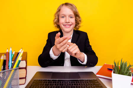 Photo of smiling young man kid having online classes education conference talking isolated on yellow color backgroundの写真素材