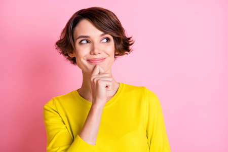 Photo portrait of happy curious girl looking empty space touching face smiling isolated on pastel pink color backgroundの写真素材
