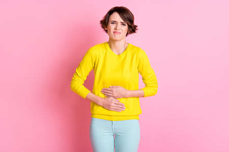 Photo of young unhappy sad stressed suffering girl hold hand on stomach pms syndrome isolated on pink color backgroundの写真素材