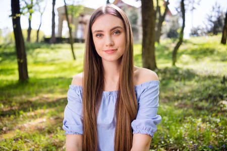 Portrait of attractive peaceful girl sitting on fresh air green grass resting at downtown outdoors