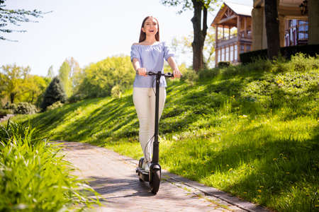 Photo of funny carefree joyful dreamy lady ride electric scooter enjoy nature park voyage wear blouse outsideの写真素材
