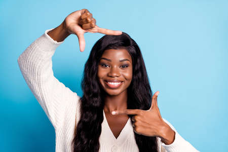 Photo portrait black skinned girl showing cadre with fingers smiling taking photo isolated bright blue color backgroundの写真素材