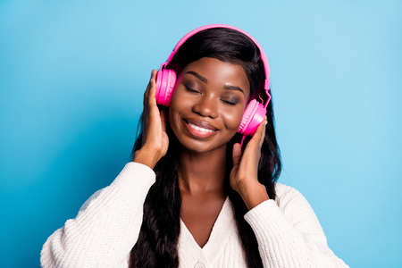 Photo of charming calm afro american young woman closed eyes enjoy music isolated on blue color backgroundの写真素材