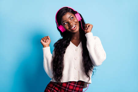 Photo of dreamy joyful afro american woman look empty space dance good music isolated on paste blue color backgroundの写真素材