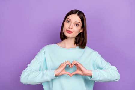 Photo portrait girl smiling showing heart sign isolated pastel violet color background