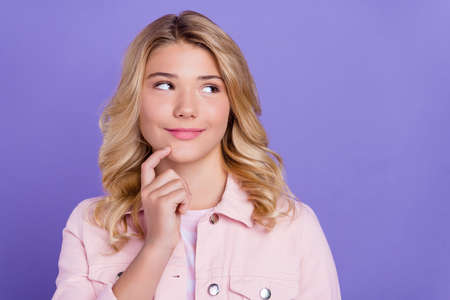 Photo of dreamy sweet schoolgirl wear pink outfit looking empty space finger chin smiling isolated violet color backgroundの写真素材