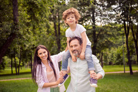 Portrait of attractive cheerful careful family dad carrying son hugging spending spare time on fresh...