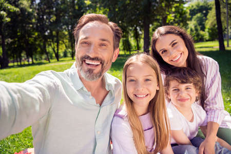 Photo of sweet charming family wear casual clothes smiling walking recording video outdoors urban city parkの写真素材