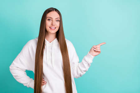 Photo of cheerful young happy woman point finger empty space good mood isolated on teal color...