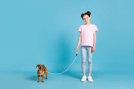 Photo of adorable cute school girl wear pink t-shirt smiling walking small friend isolated blue color backgroundの写真素材