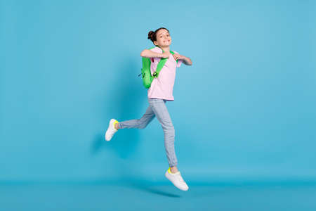 Full length photo of cheerful young happy girl jump up wear backpack walk isolated on blue color...