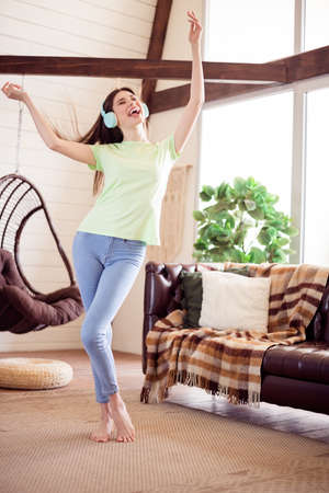Vertical full length body size view of attractive cheerful ecstatic girl listening music free time having fun at house flat indoorsの写真素材