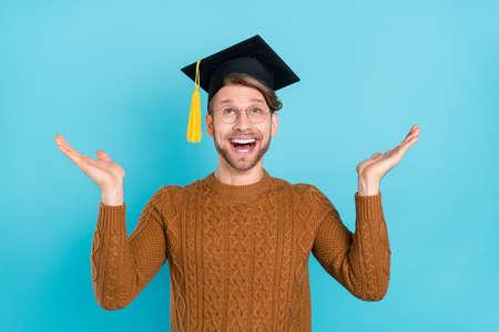Photo of cheerful amazed happy young man look empty space wear hat glasses isolated on blue color...