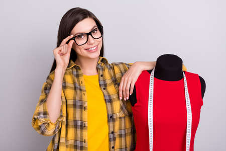 Photo of young woman happy positive smile hand touch glasses mannequin stylist isolated over grey...