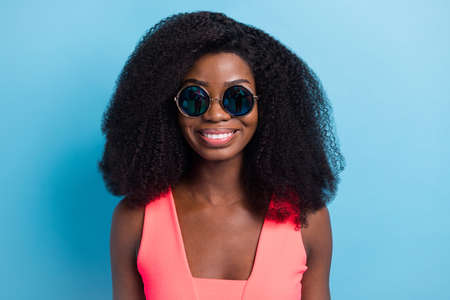 Photo portrait of pretty girl curly hairstyle smiling in sunglass pink dress isolated vivid blue...