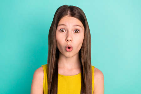 Photo of impressed nice brown hair girl wear yellow dress isolated on bright teal color backgroundの写真素材