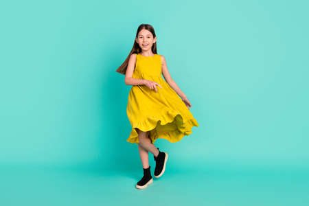 Full size photo of optimistic nice brown hair girl dance wear yellow dress shoes isolated on bright teal color backgroundの写真素材