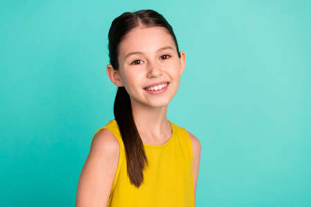 Photo of optimistic nice brown hair girl wear yellow dress isolated on bright teal color backgroundの写真素材