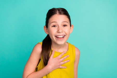 Photo of optimistic nice brown hair girl wear yellow dress isolated on bright teal color backgroundの写真素材