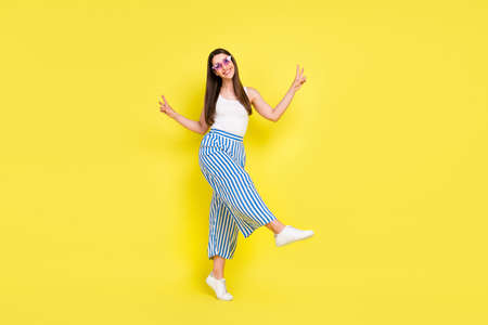Full length body size view of charming cheerful girl dancing showing v-sign having fun isolated over...