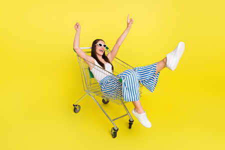 Full length photo of funny brunette lady sit in trunk wear top pants spactacles isolated on yellow color backgroundの写真素材