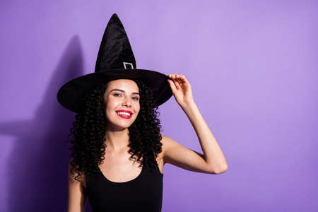 Photo of young beautiful happy smiling cheerful witch girl in cone shape hat isolated on violet...